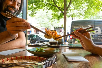 Gäste teilen knusprige Teigtaschen mit Stäbchen im Comcha Vegan Restaurant